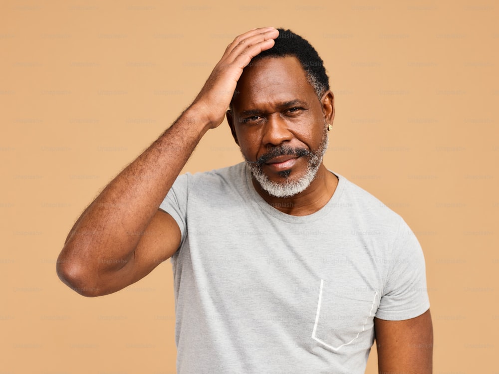 a man in a gray shirt is holding his head