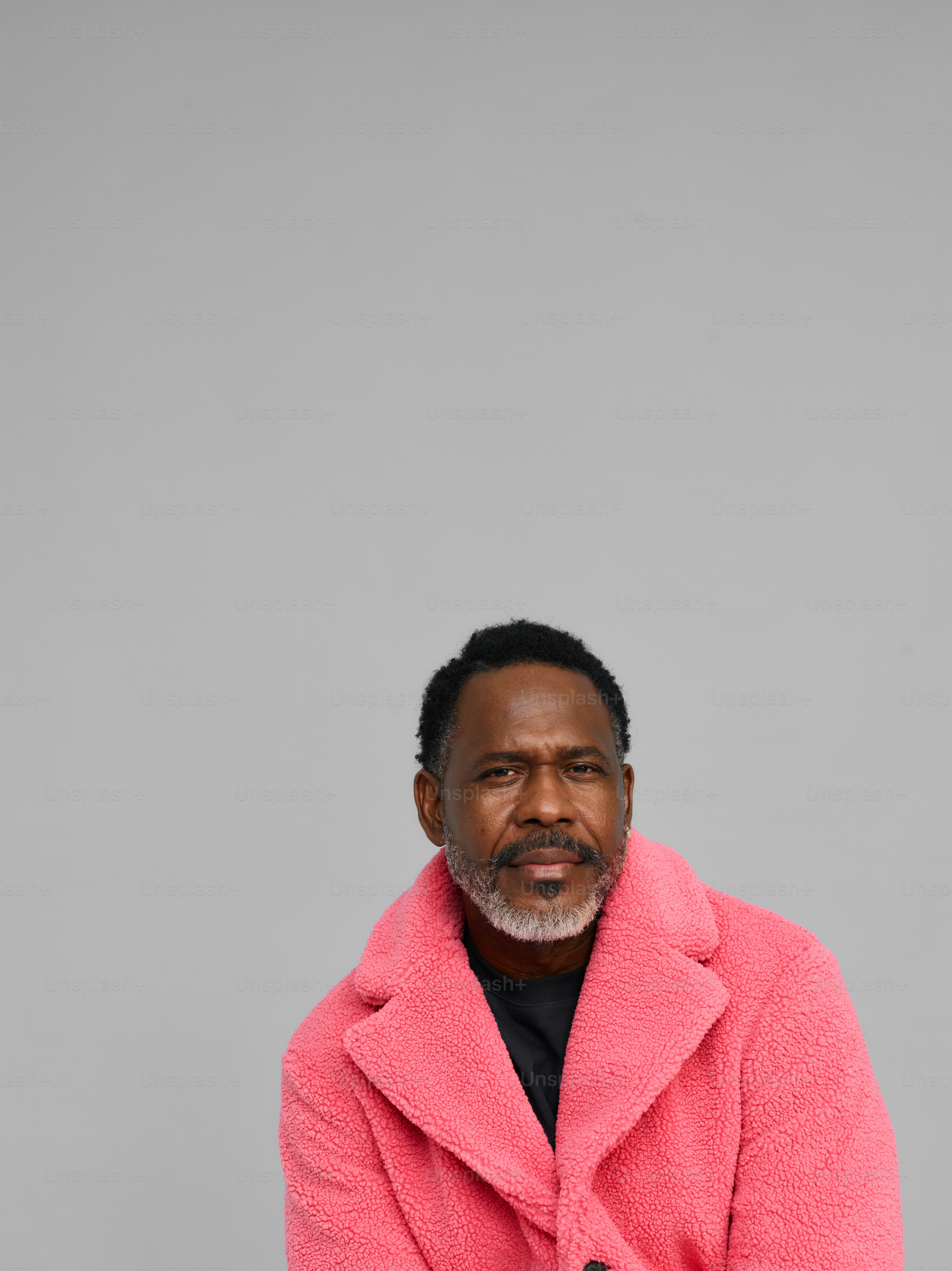 um homem de casaco rosa posando para uma foto