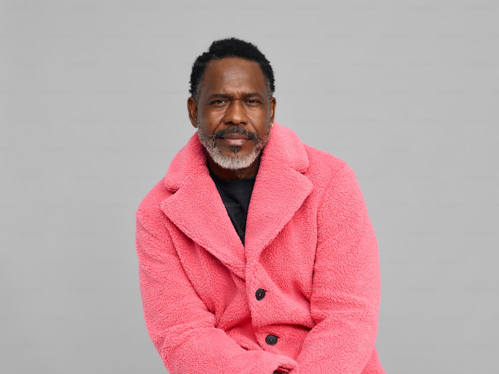 분홍색 코트를 입은 남자가 사진을 찍기 위해 포즈를 취하고 있다