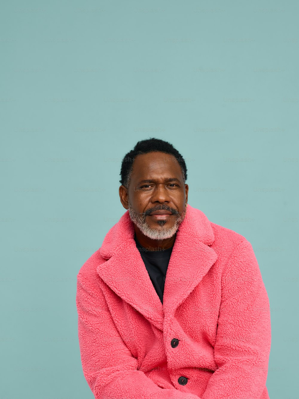 Ein Mann in einem rosa Mantel sitzt auf einem Stuhl
