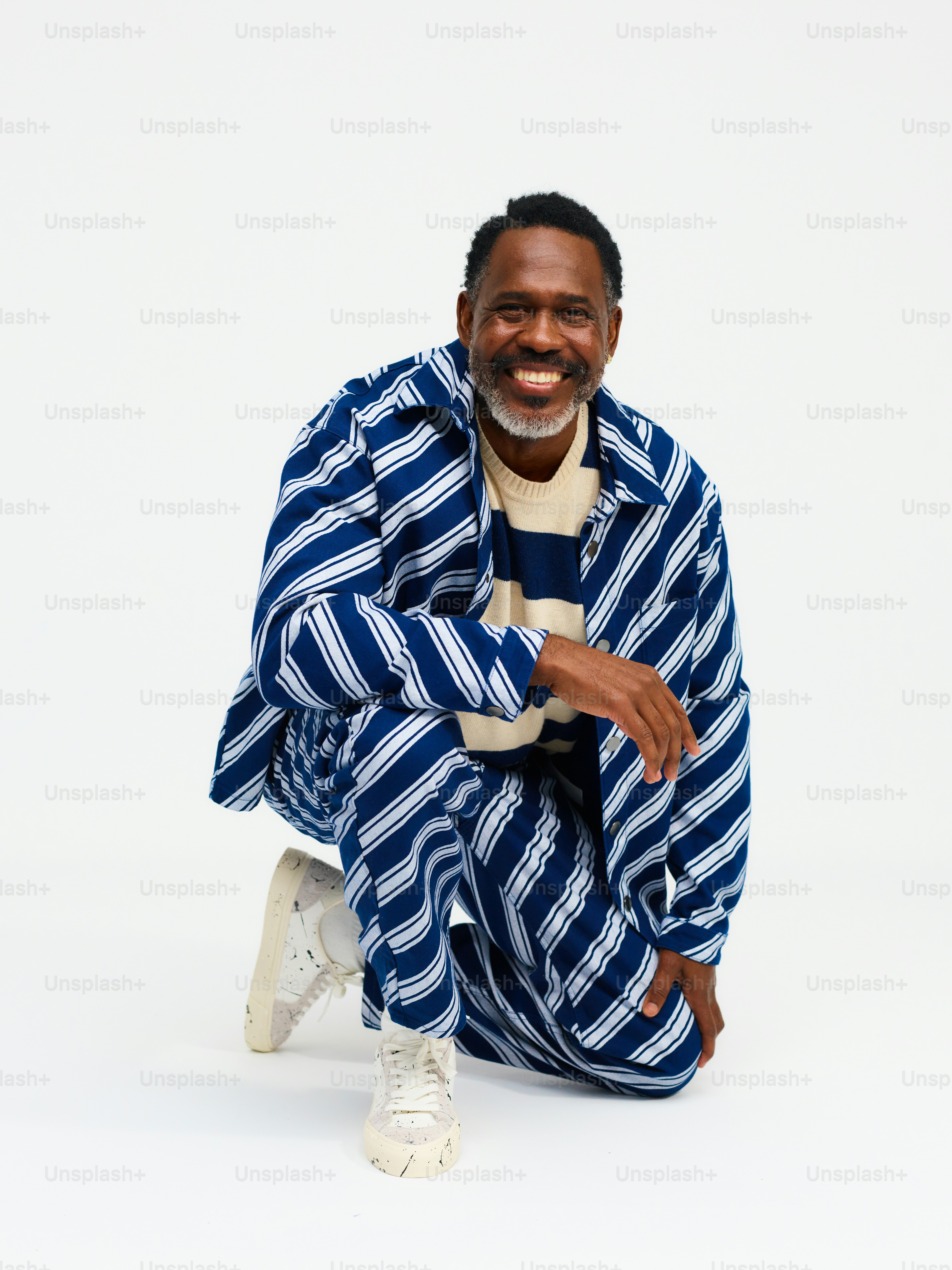 um homem sentado no chão vestindo um terno listrado azul e branco