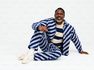 a man sitting on the ground wearing a blue and white striped suit