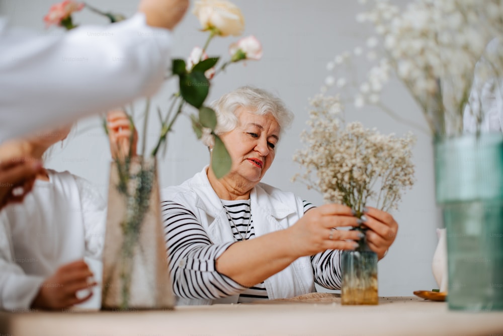una mujer arreglando flores en un jarrón sobre una mesa