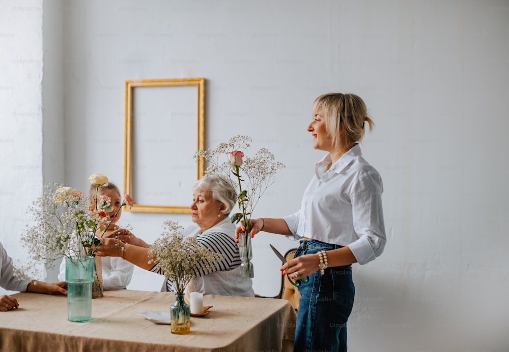 un grupo de personas de pie alrededor de una mesa con flores en jarrones