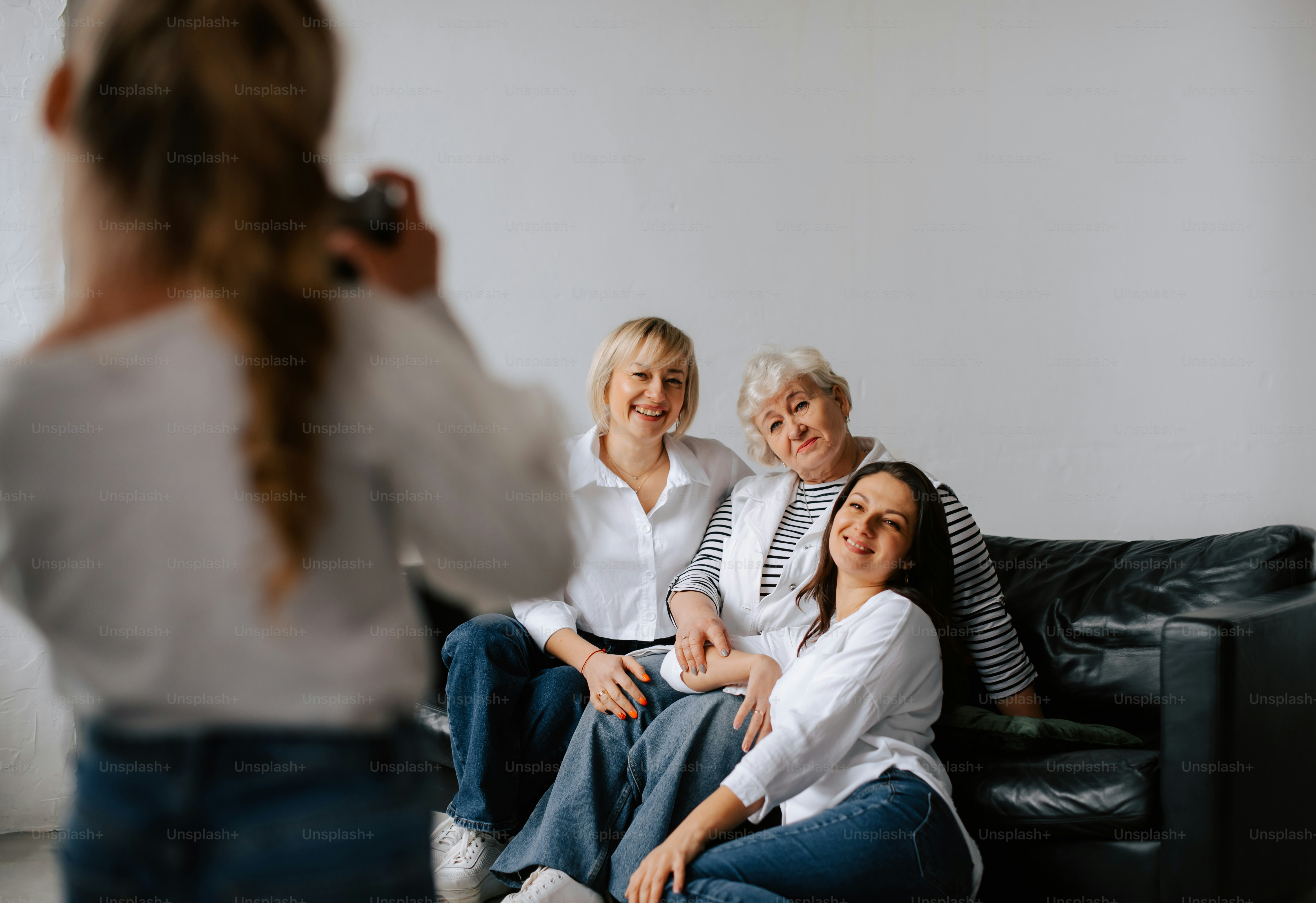 eine Frau, die ein Foto von zwei Frauen macht, die auf einer Couch sitzen