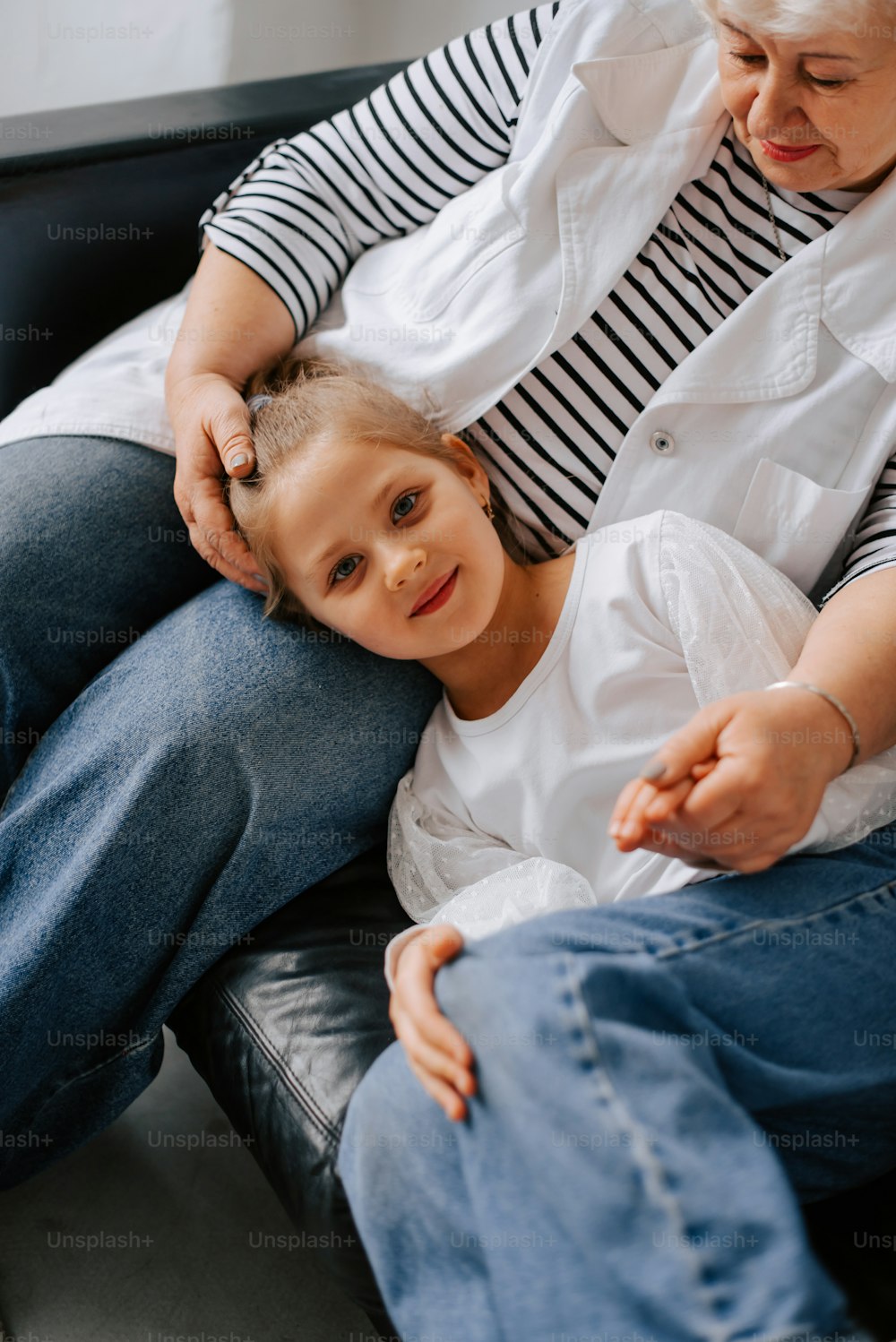 a woman sitting next to a child on a couch