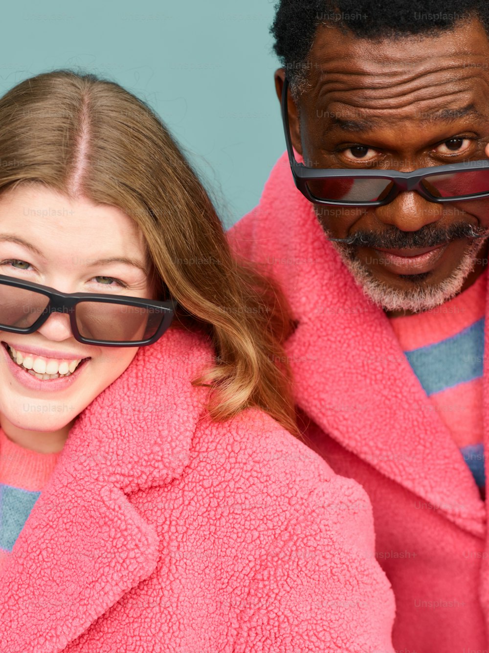um homem e uma mulher usando óculos escuros e um casaco rosa