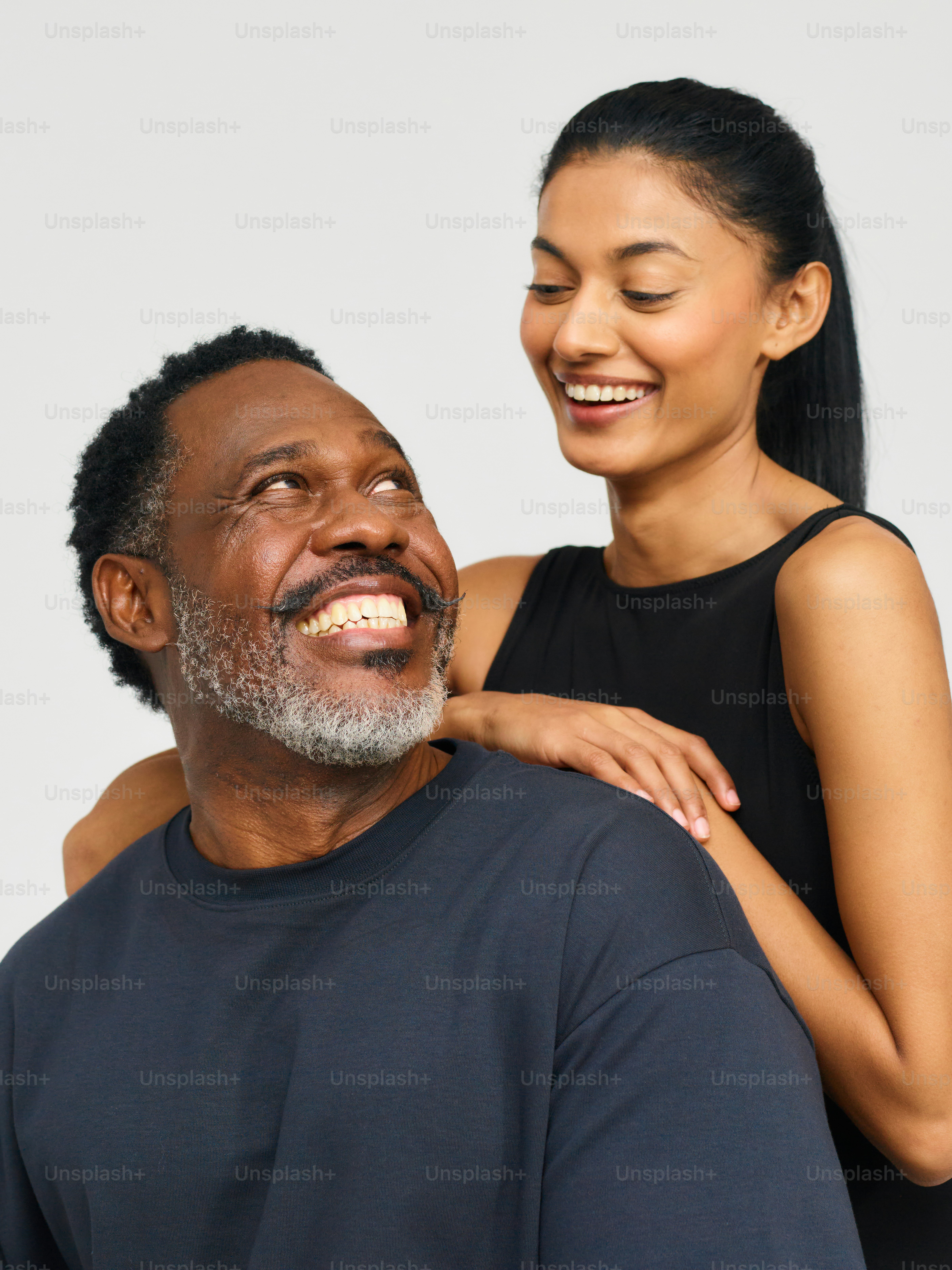 a woman smiles as a man holds his arm around him