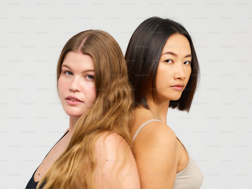 duas mulheres em pé uma ao lado da outra em frente a um fundo branco