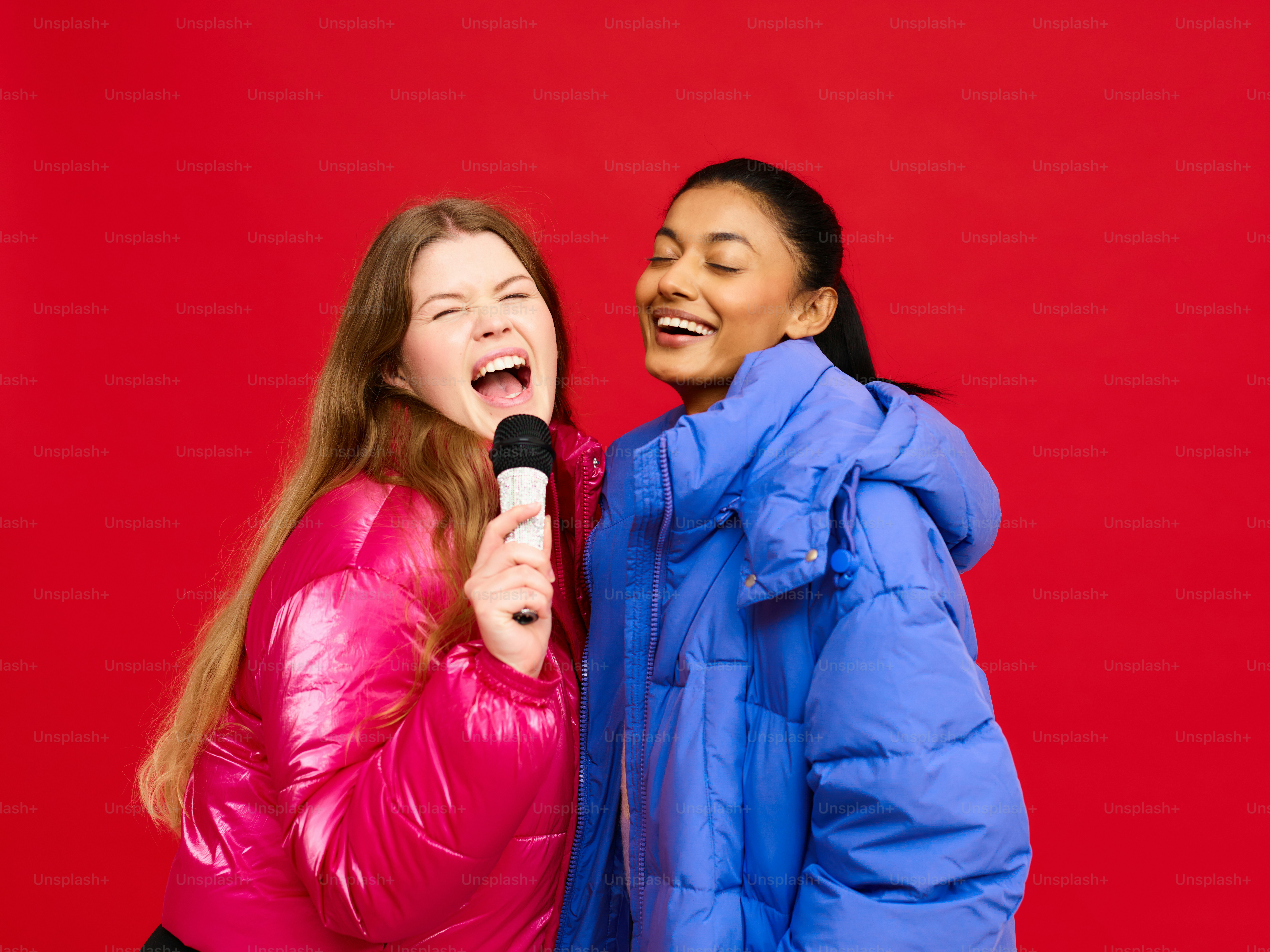 two women are laughing while one of them is holding a microphone