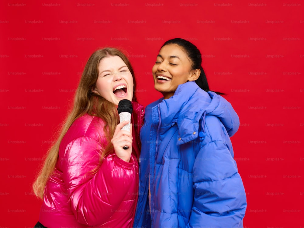 two women are laughing while one of them is holding a microphone