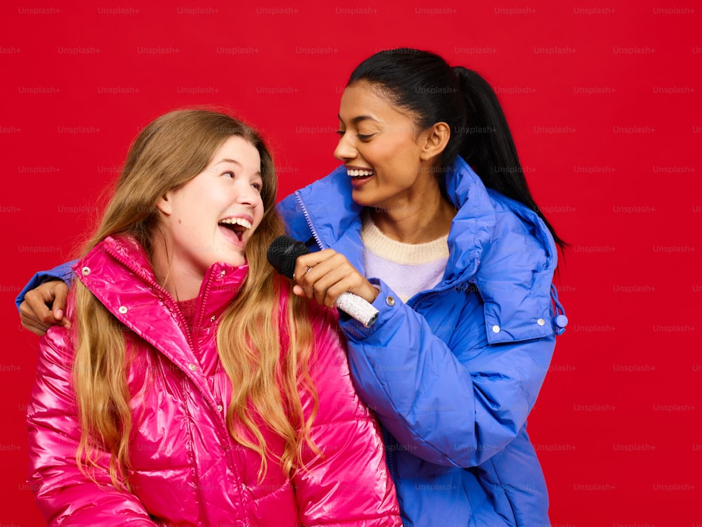 two girls are laughing while one of them is holding a microphone