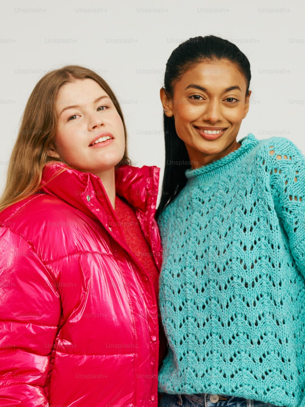two women standing next to each other wearing jackets