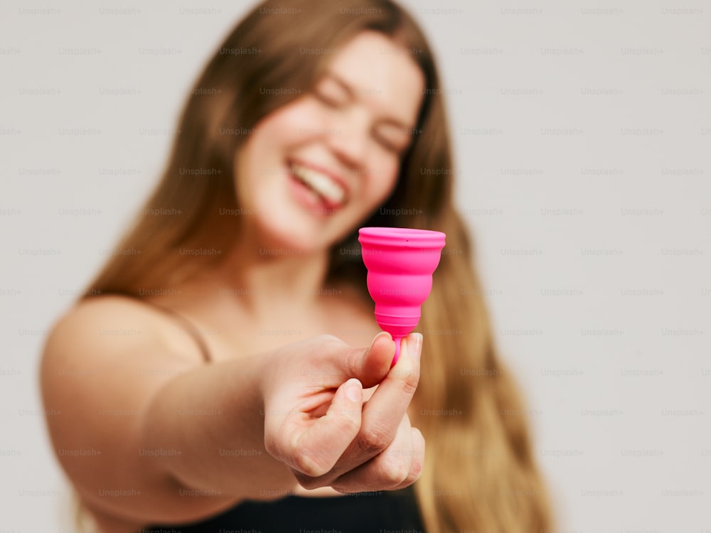 a woman holding a pink cup in her hand