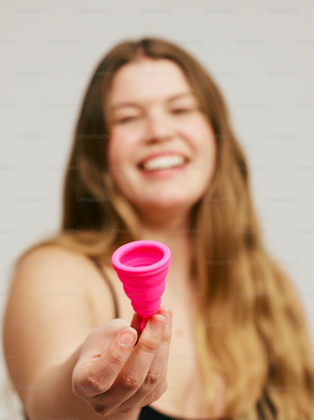 una mujer sosteniendo una taza rosa en la mano