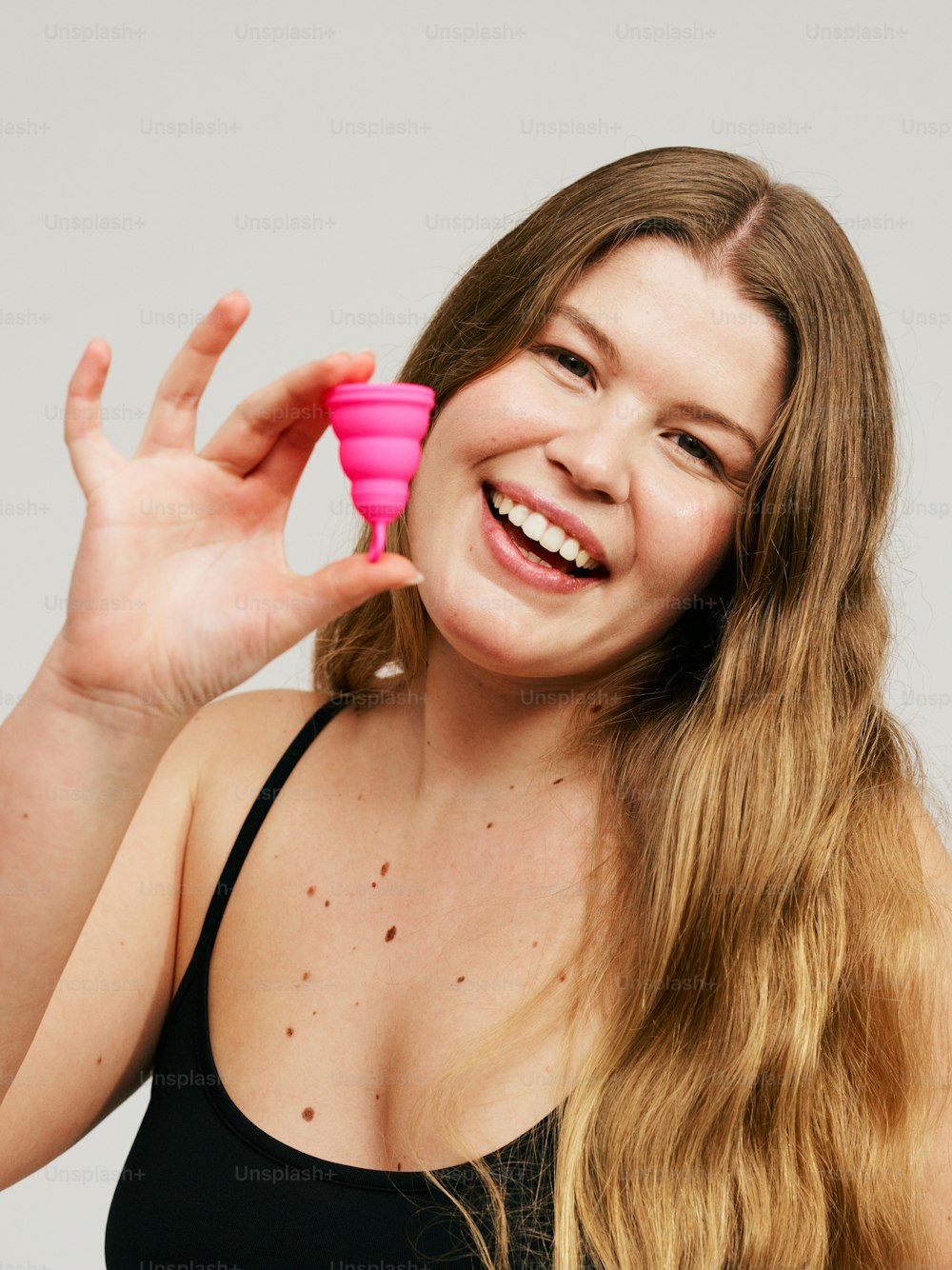 una mujer sosteniendo un objeto rosa frente a su cara