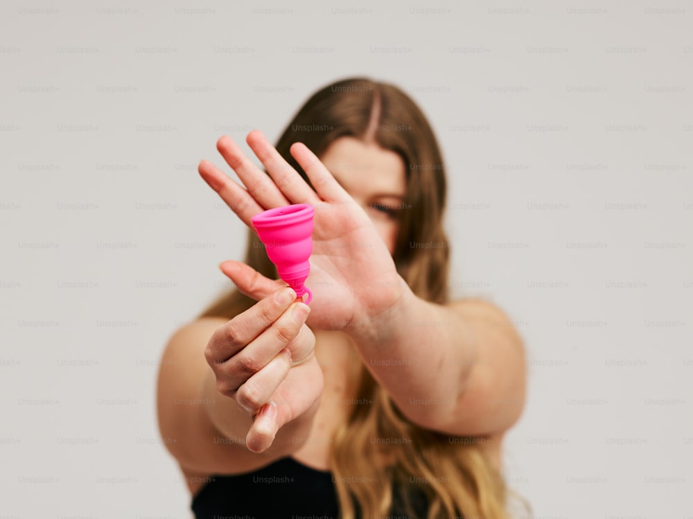 una mujer sosteniendo una taza rosa en la mano