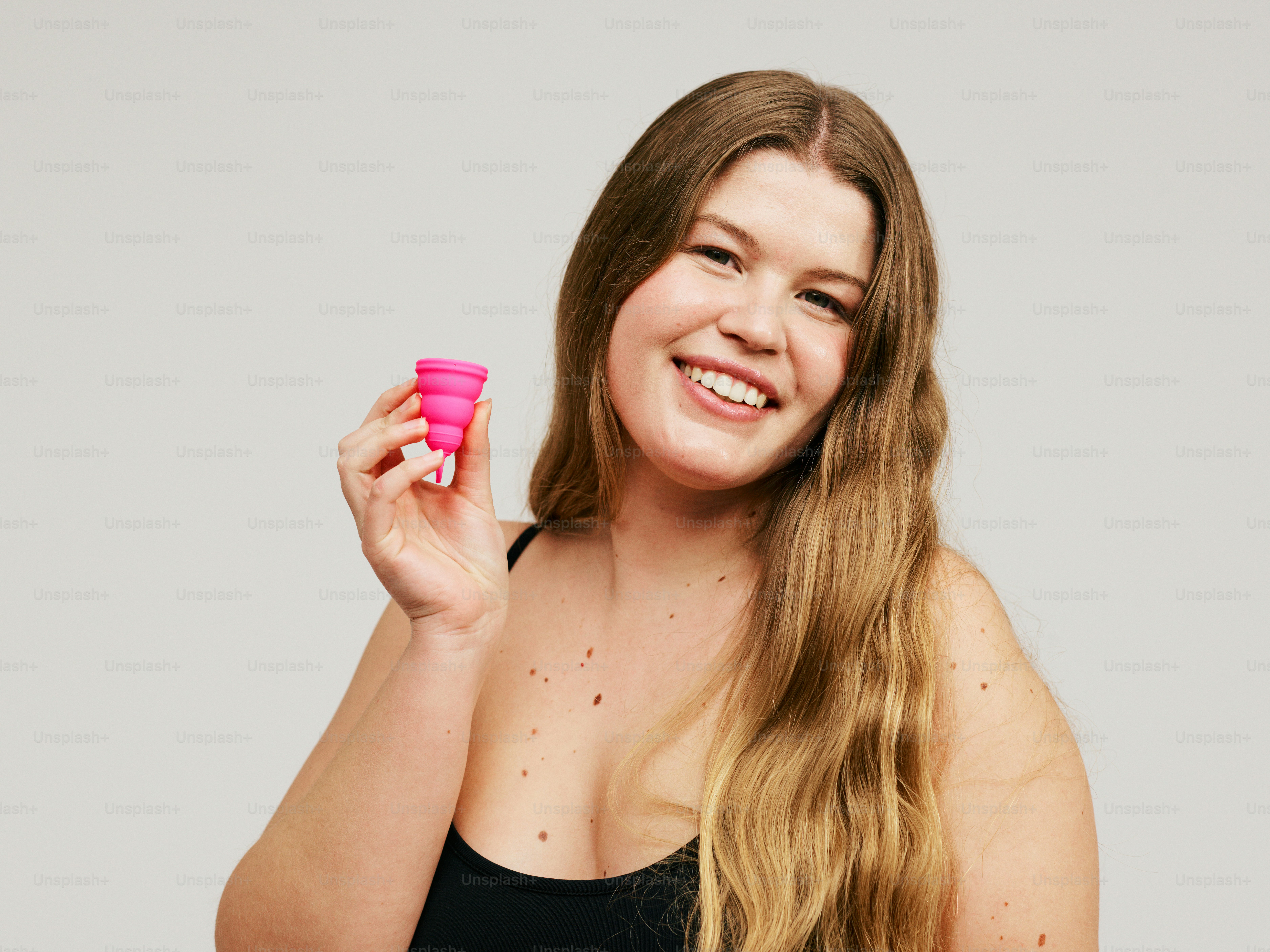 eine Frau, die einen rosa Becher in der rechten Hand hält