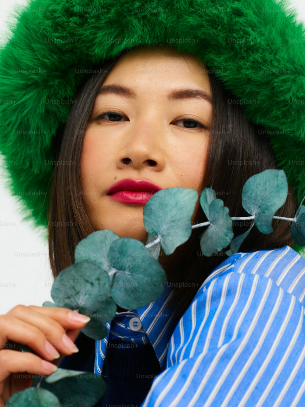 a woman wearing a green hat and holding leaves