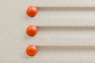 three orange balls sitting on top of a white surface