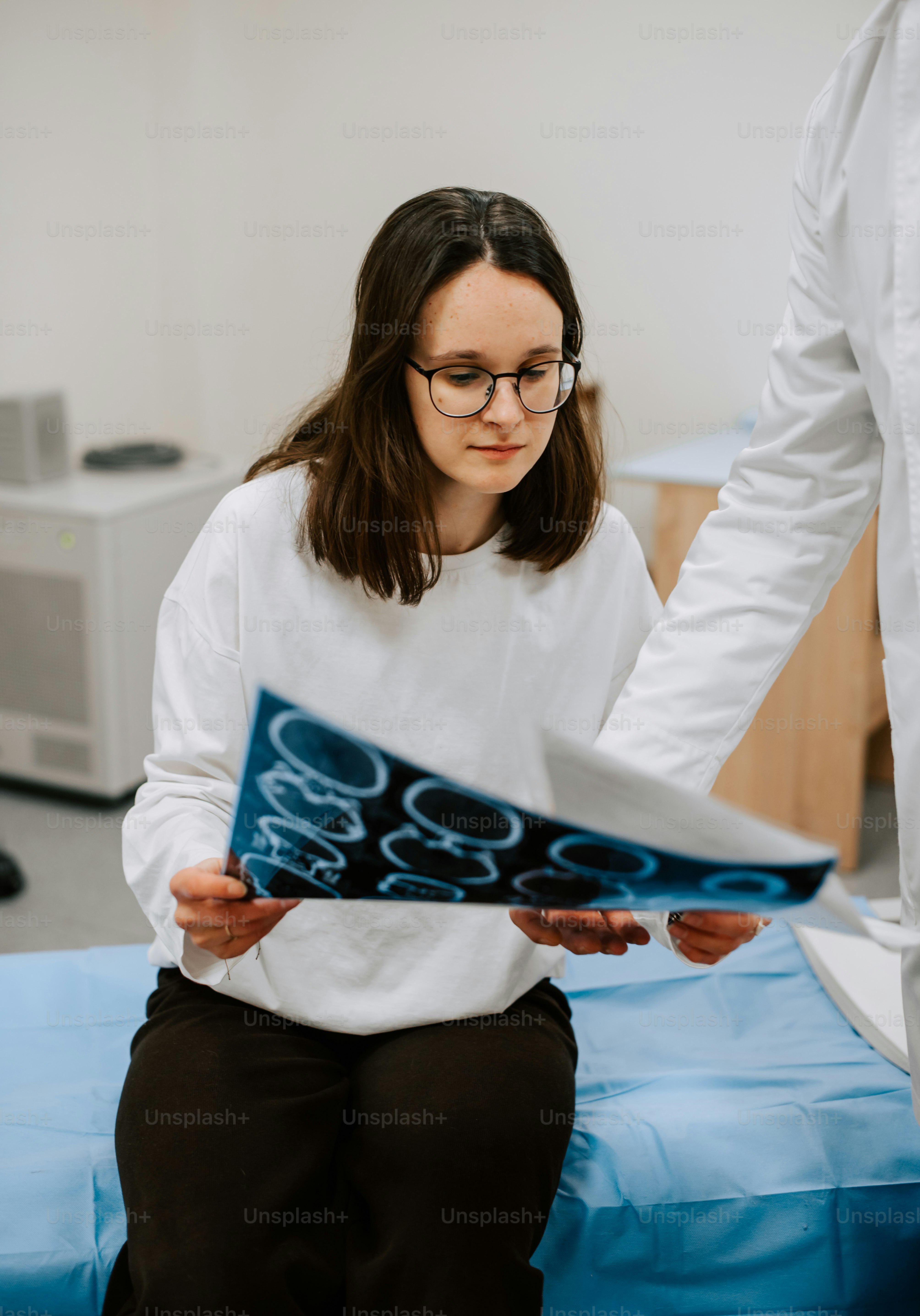 eine Frau, die auf einem Bett sitzt und ein Blatt Papier in der Hand hält