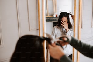 a woman blow drying her hair in front of a mirror