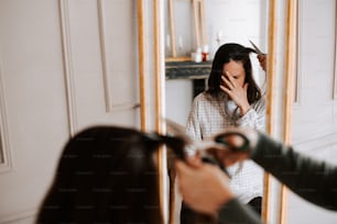 una mujer secándose el pelo frente a un espejo