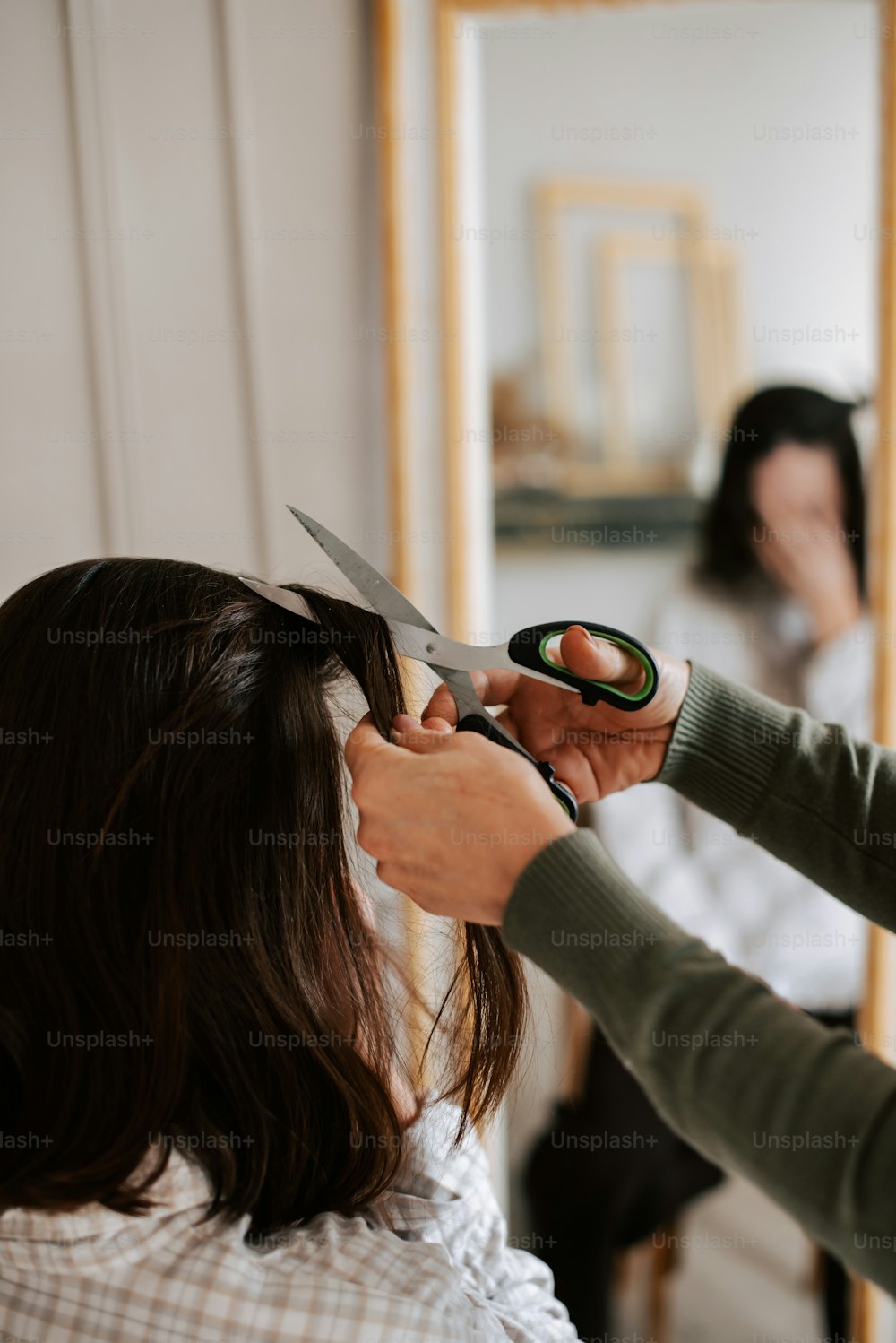 a woman cutting another woman's hair with a pair of scissors