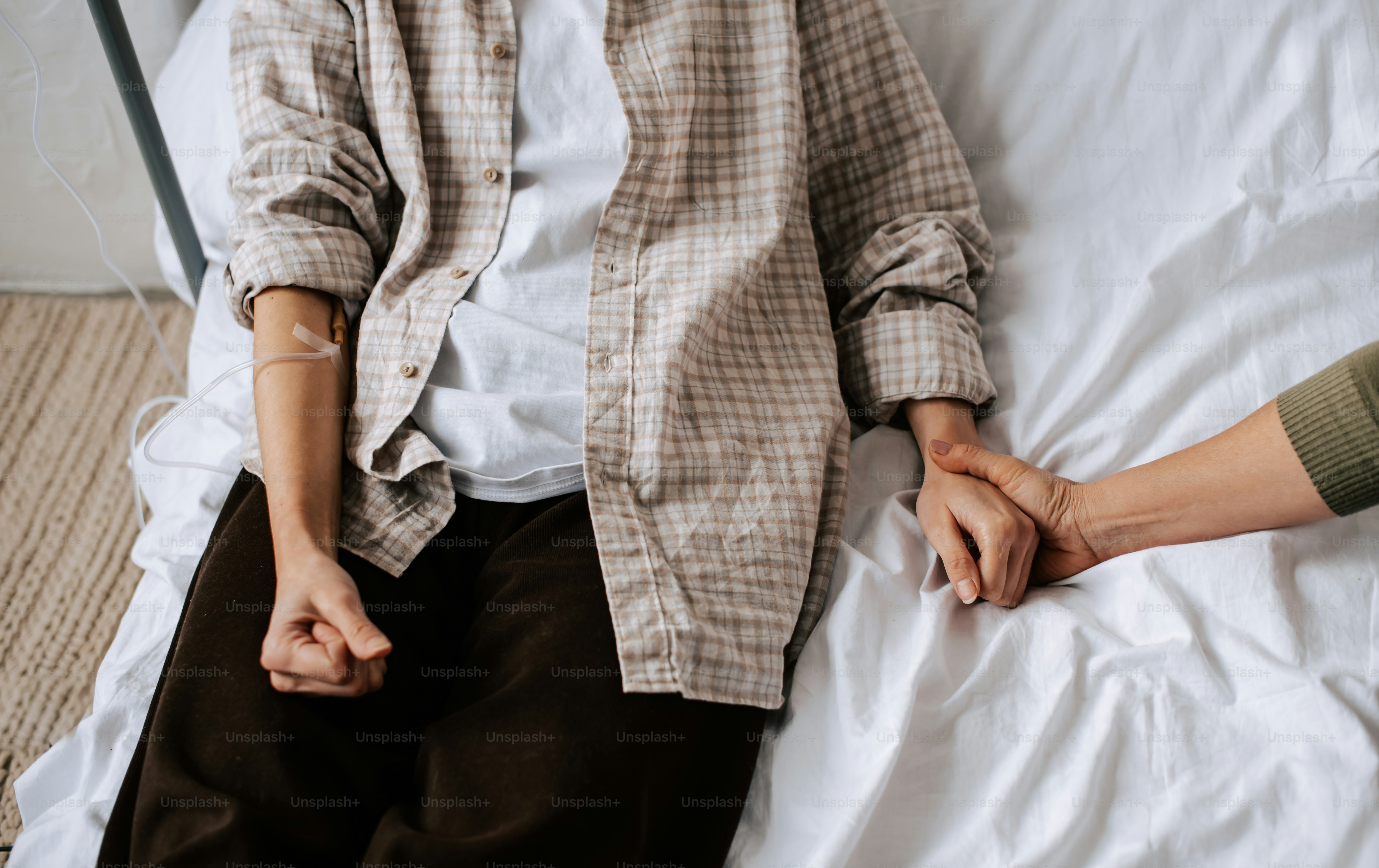 eine Person, die auf einem Bett sitzt und ihre Hand auf dem Fuß einer anderen Person hat