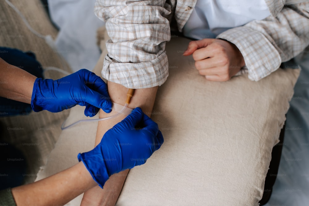 a person in blue gloves is performing a procedure on another person's leg