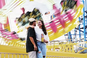 Un hombre y una mujer de pie frente a una atracción de carnaval