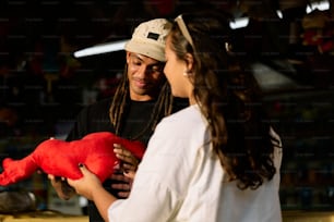 a man holding a red stuffed animal next to a woman