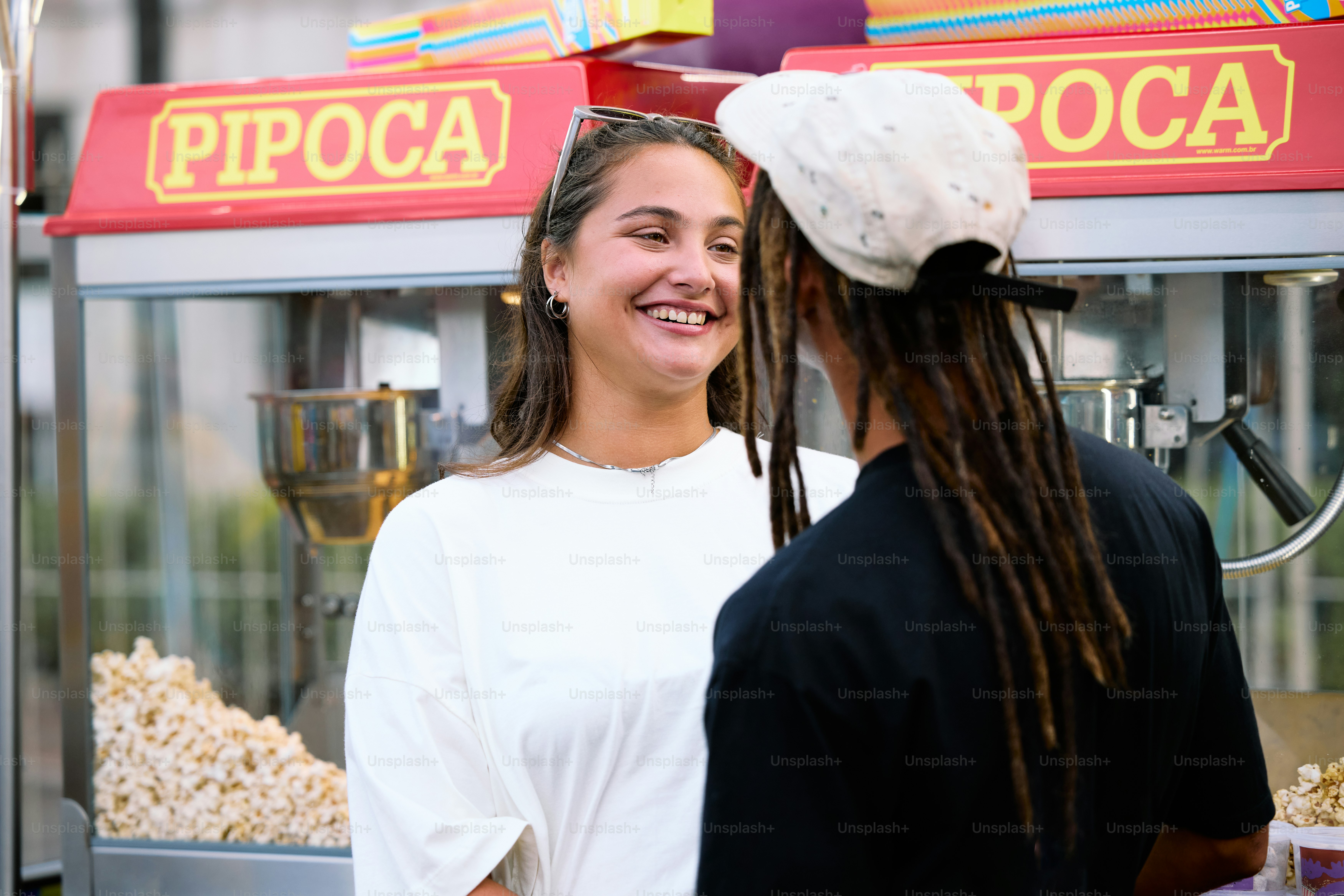 a couple of people standing in front of a popcorn machine