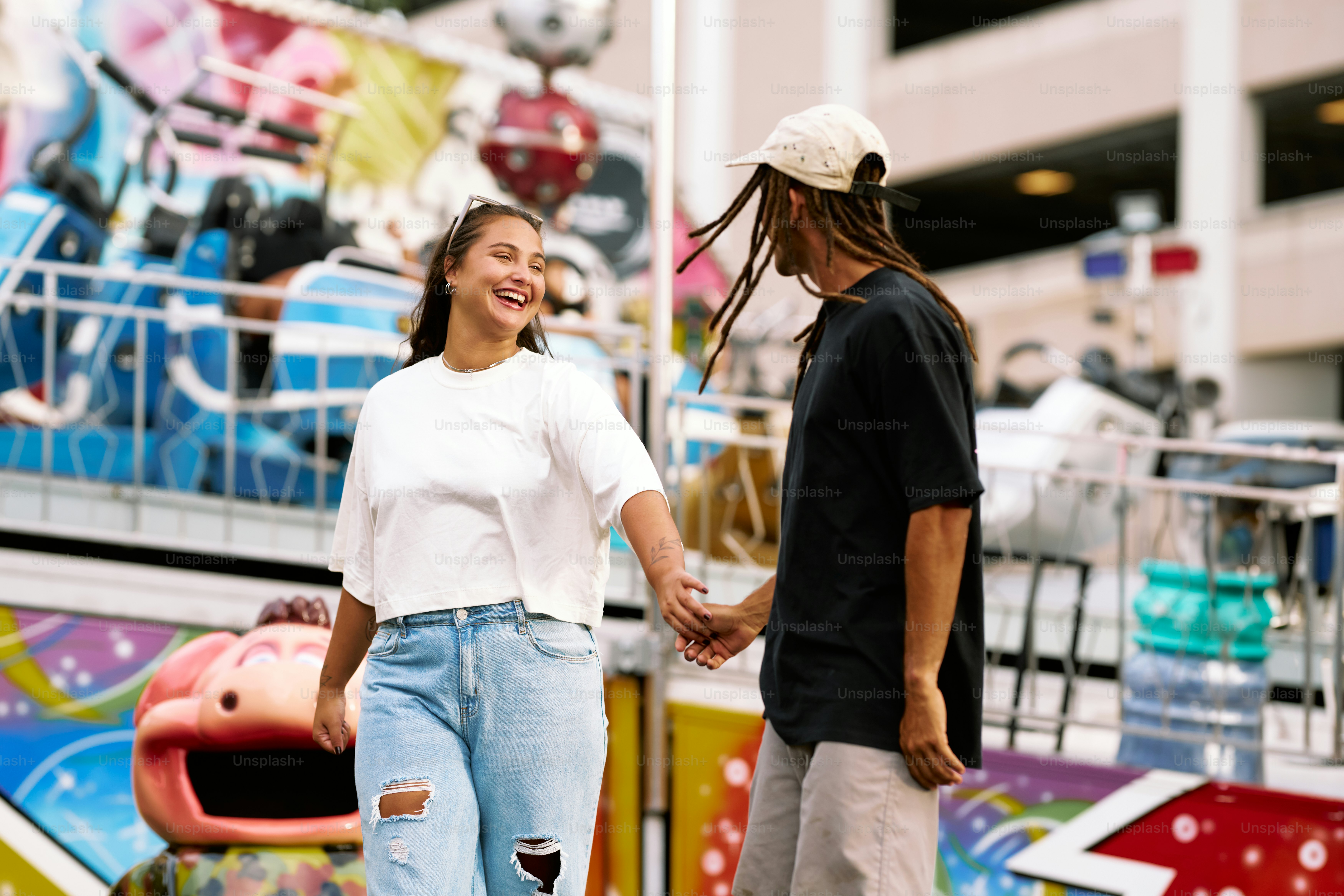 a man and a woman holding hands in front of a carnival ride