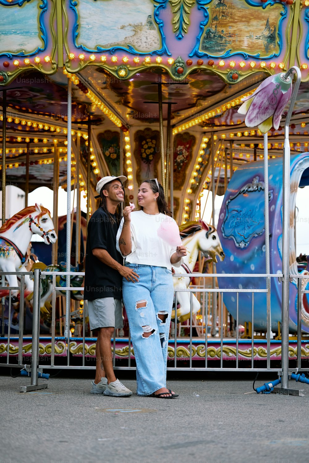 a man and a woman standing in front of a carousel