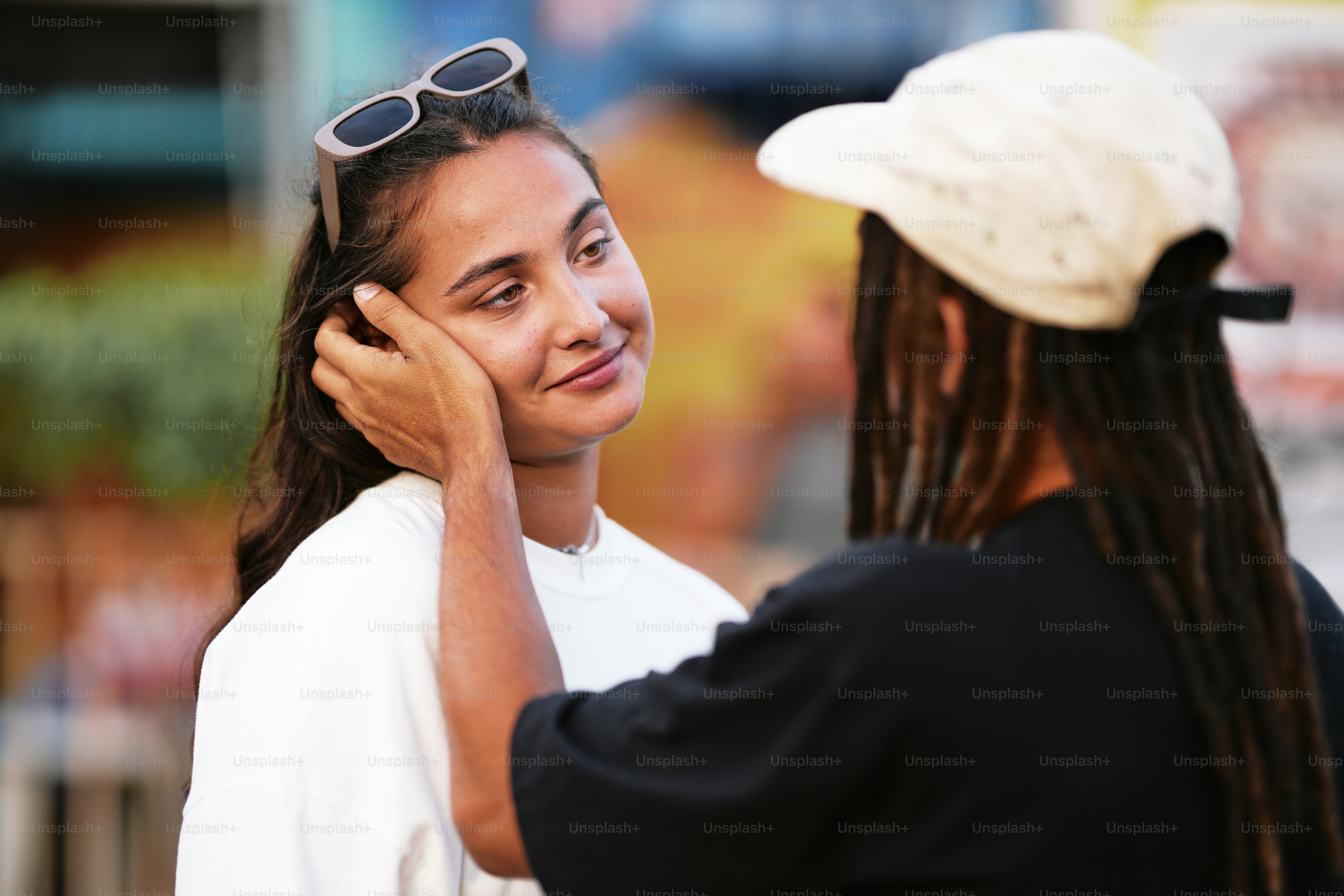 a woman with a hat and sunglasses talking to another woman