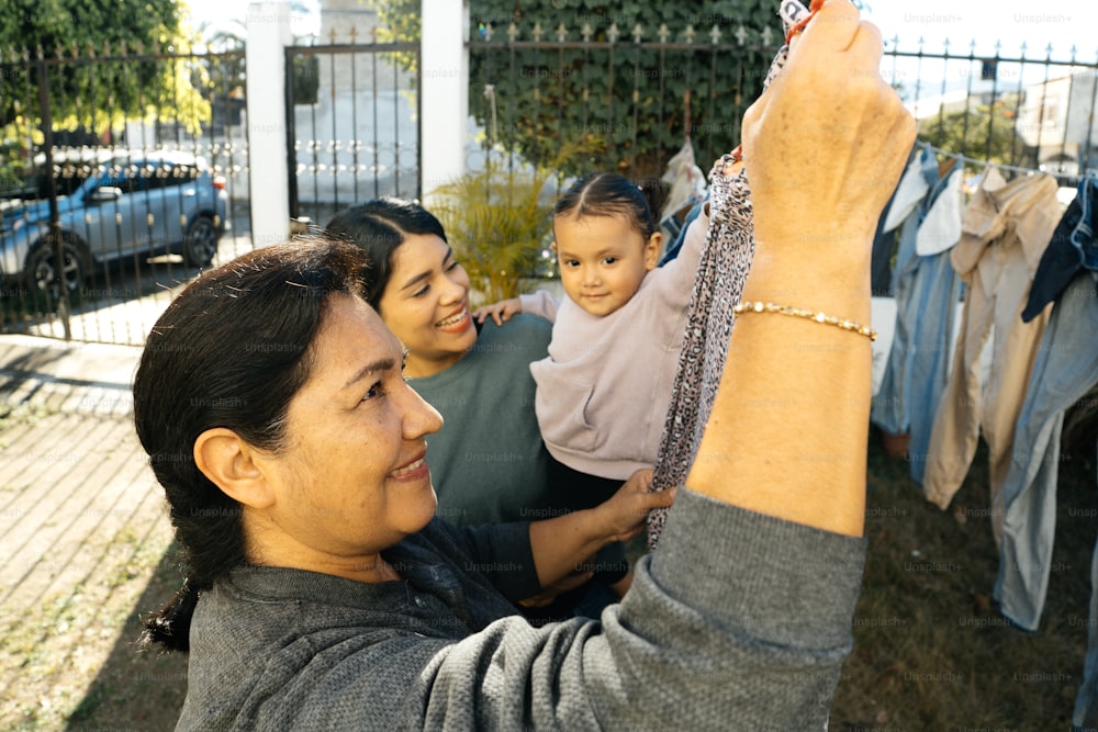 a woman holding a baby up to a clothes line