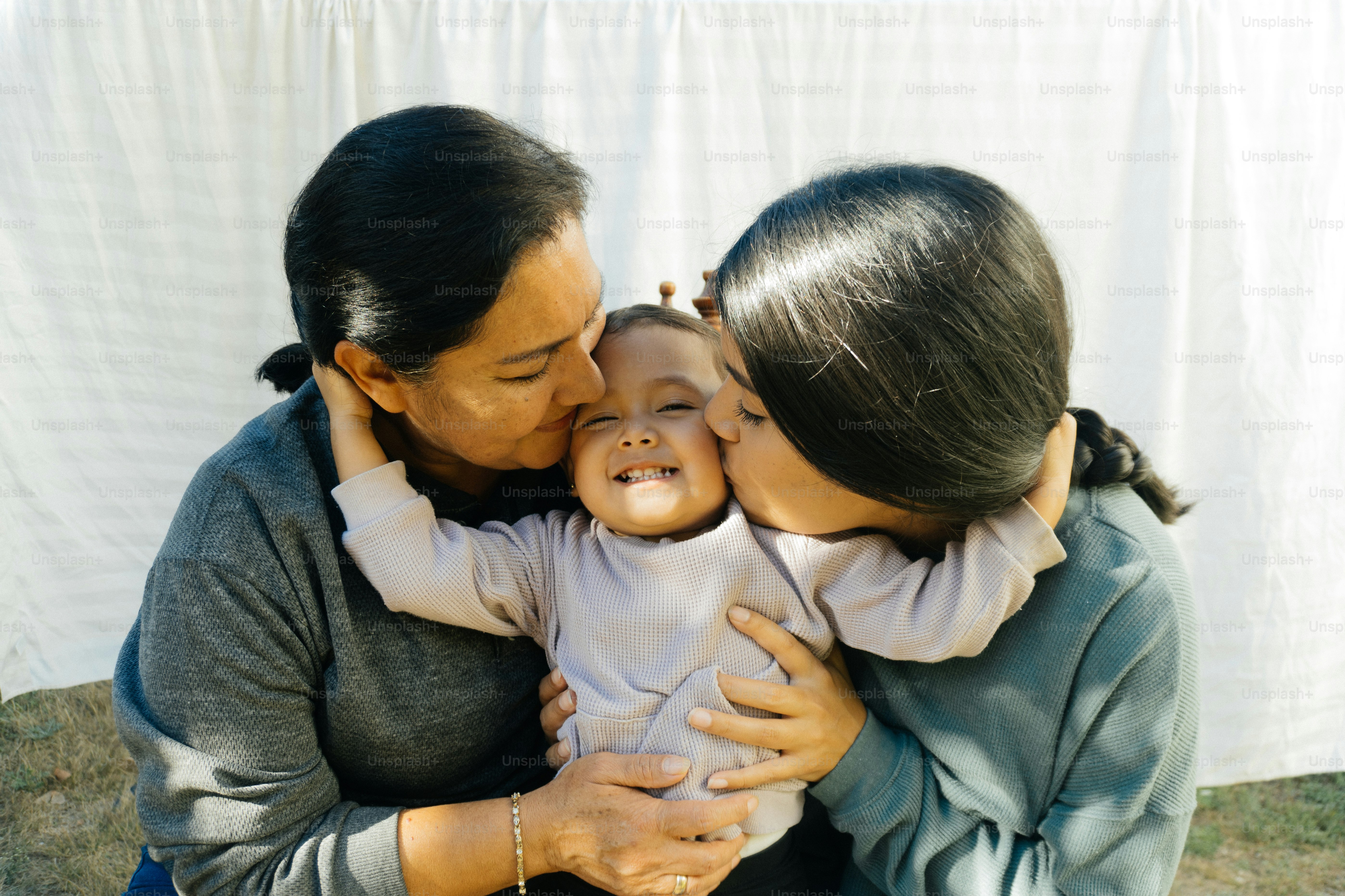 a woman holding a baby and kissing her cheek