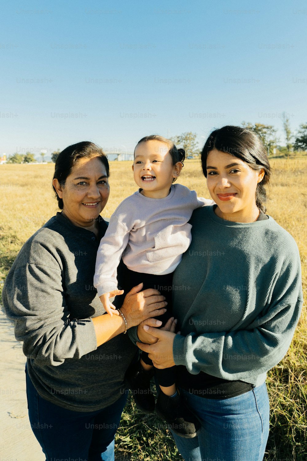 a woman holding a baby standing next to a woman
