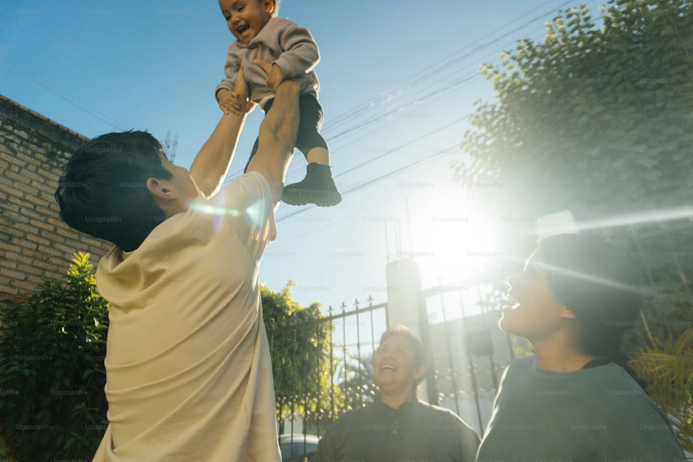 a man holding a baby up in the air