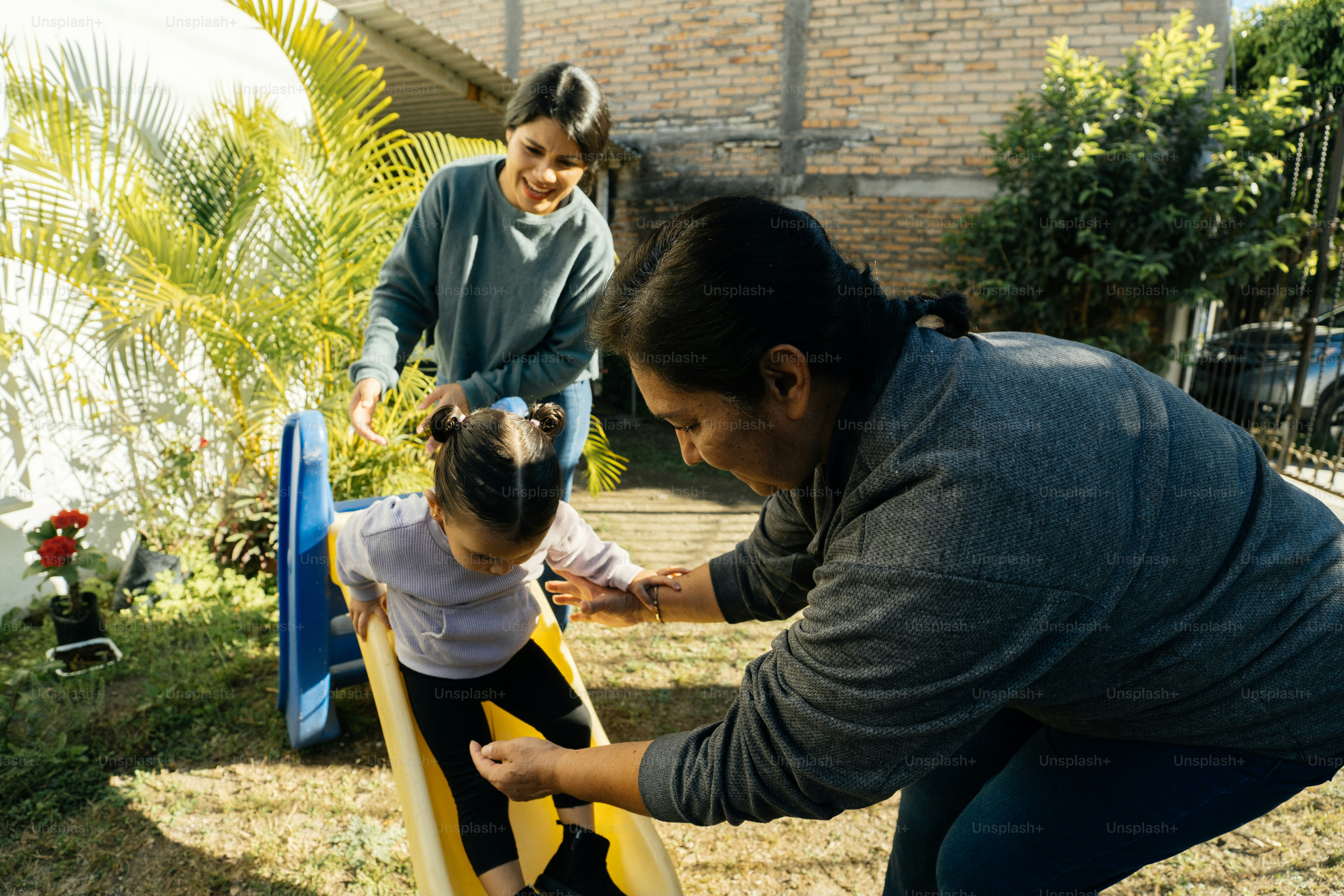 a woman helping a little girl play on a slide