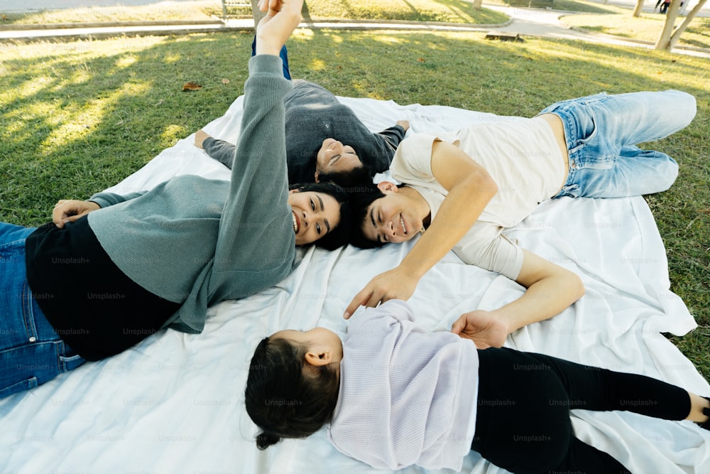 a group of people laying on top of a white blanket