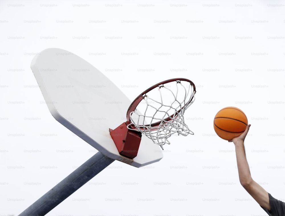 Eine Person wirft einen Basketball in einen Basketballkorb