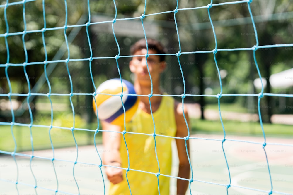 a man in a yellow shirt is playing volleyball