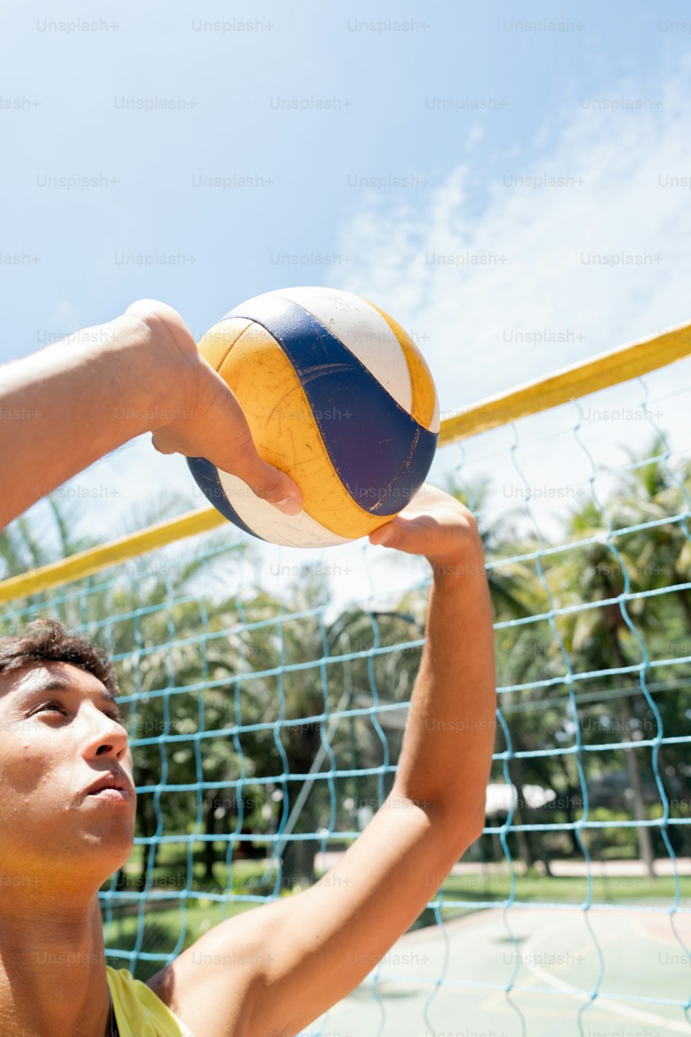 a young man holding a volleyball over a net