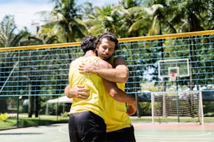 two men hugging each other on a tennis court