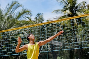 a man in a yellow shirt is playing volleyball
