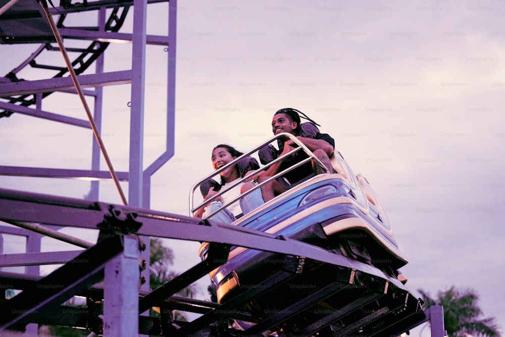 two people riding a roller coaster on a cloudy day