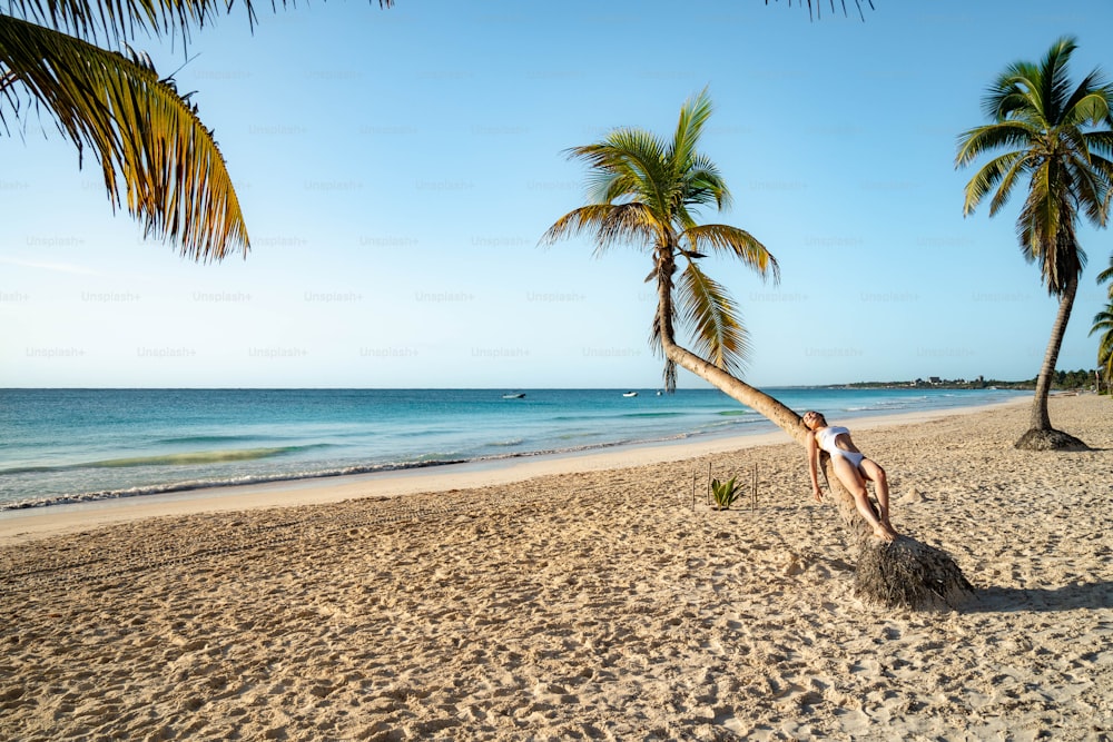 a man standing on a beach next to a palm tree