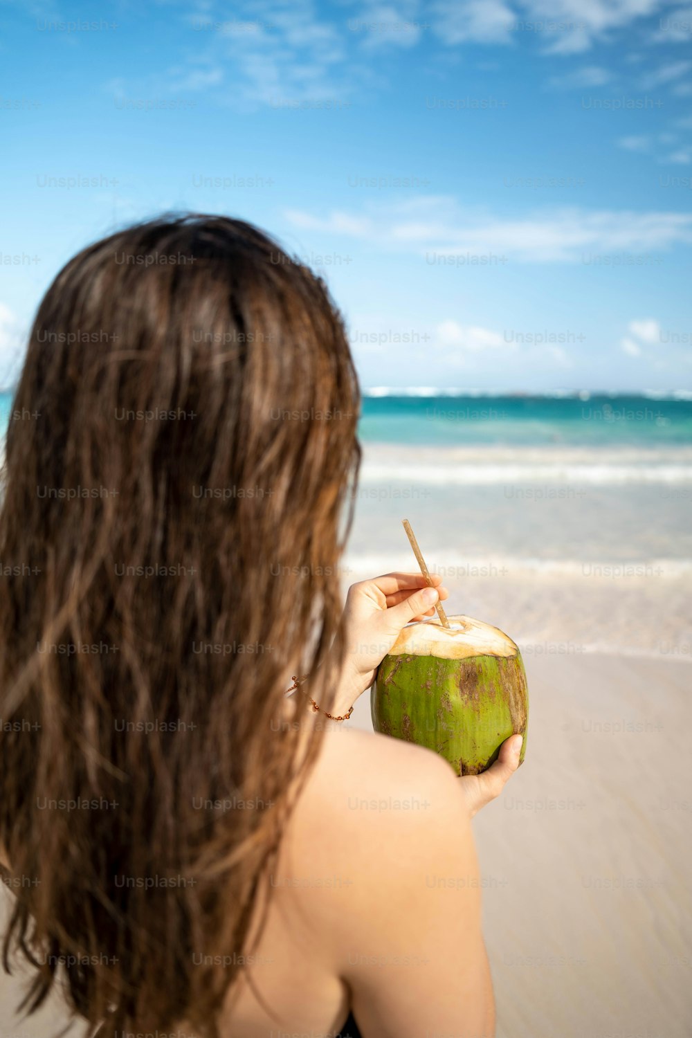 a woman holding a coconut on the beach